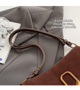 Detailed close-up of dark brown suede shoulder bag with textured gold metallic buckle hardware