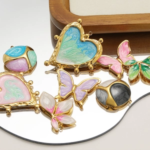 Macro shot of gold-plated butterfly and heart pendants with colorful enamel drip oil texture