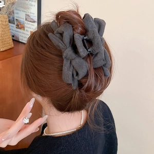 Detailed back view of a large charcoal grey fabric bow claw clip in an elegant hairstyle