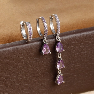 Macro detail of silver drop earrings set with purple pear-shaped zircon stones
