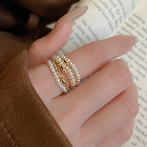 Detail of multilayer ring featuring faux pearls and gold beads worn on a finger
