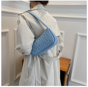 Close-up of light blue shoulder bag featuring detailed pleated texture and quilting