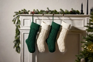Detail of dark green and cream knitted Christmas stockings hanging on a white fireplace