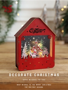 Detail of red wooden Christmas house ornament with warm LED light and Santa scene