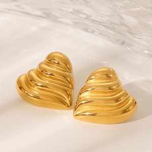Close-up of golden heart-shaped stud earrings with textured wavy design surface