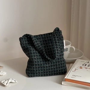 Close-up of green plaid tweed handbag featuring a decorative simple wish brand label