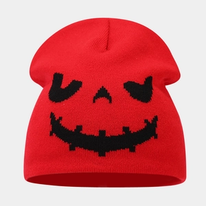 Close-up of red knit beanie featuring a black woven Halloween pumpkin face pattern