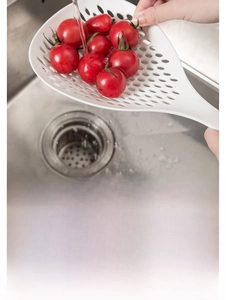 Detail of white nylon slotted spoon for draining water and washing fruit in kitchen sink