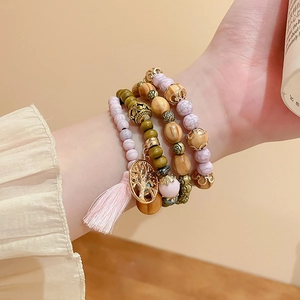 Detail of bohemian multilayer sandalwood beaded bracelets with Tree of Life charm and tassel