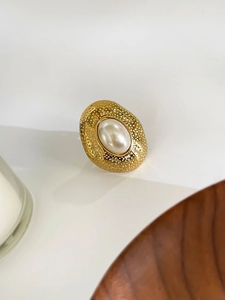Macro shot of 18k gold pearl ring featuring vintage hammer texture on the metal band
