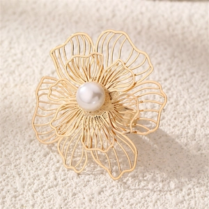 Macro detail of golden metal hollow flower jewelry with white pearl center