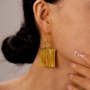 Close-up of elegant gold tassel earrings with irregular knots worn by a female model