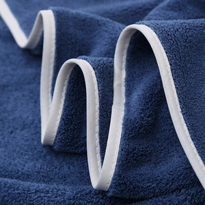 Macro shot of thick navy blue coral fleece towel with elegant white ribbon edging