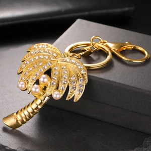 Porte-clés palmier doré orné de strass et perles sur un élégant fond noir