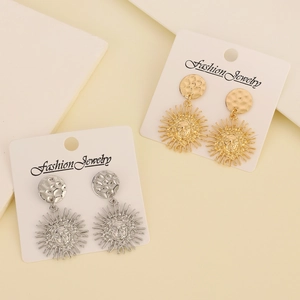 Detail of sun mask face earrings featuring textured metallic hammered finish in gold and silver