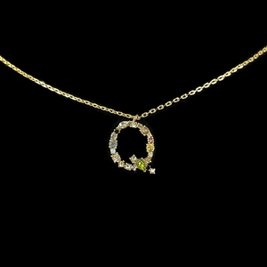 Macro shot of 18k gold letter Q pendant featuring colorful inlaid zircon stones