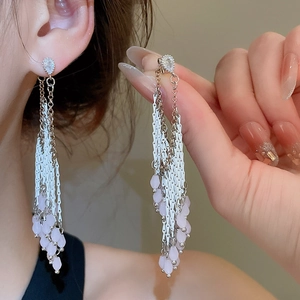 Détail de boucles d'oreilles pompon en argent avec perles roses et pierres de zircon