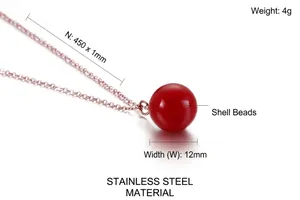 Détail du pendentif perle rouge sur une chaîne minimaliste en acier inoxydable