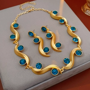 Detailed view of vintage gold wavy jewelry set with blue rhinestones in a velvet box