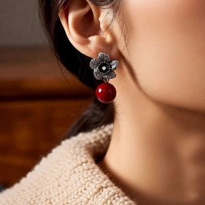 Detail of vintage flower earrings with silver finish and red round bead pendant
