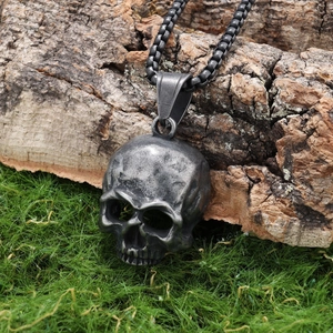 Detailed close-up of a vintage skull pendant on a rustic tree bark with green moss