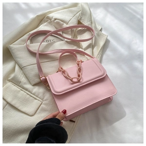 Pink PU leather square bag with thick chain handle and gold hardware on white fabric