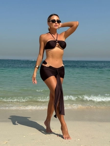 Detail view of black three-piece bikini with metallic ring buckle and draped skirt detail