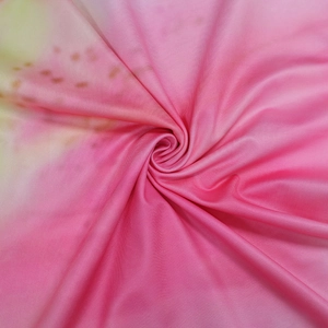 Détail du tissu dégradé rose et jaune montrant une texture lisse et un motif tacheté