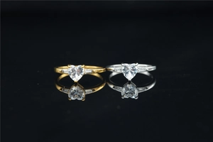 Close-up of gold and silver heart-shaped moissanite rings with side trapezoid diamonds