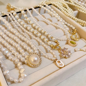 Détail de colliers de perles vintage français avec pendentifs dorés dans un plateau