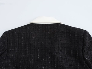 Détail de l'encolure dos du manteau en tweed montrant la texture tissée noir et blanc