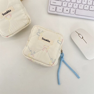 Detail of cream quilted organizer bag with rabbit embroidery and blue cord on desk