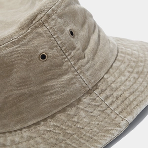 Detail of washed khaki bucket hat featuring vintage metal eyelets and reinforced stitching