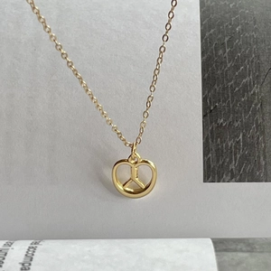 Detail of a 925 sterling silver heart-shaped peace sign pendant in gold finish
