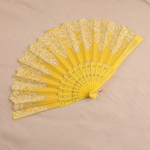 Spanish style yellow lace folding fan with floral patterns and gold accents on plastic frame