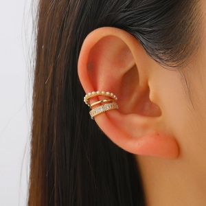 Detailed view of three-piece gold ear cuff set with pearls and zircons on model ear