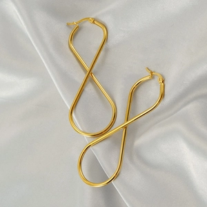 Elegant gold infinity twist drop earrings displayed on white silk fabric background