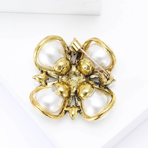 Macro shot of vintage gold floral brooch with pearls and metal pin clasp detail