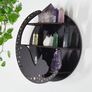 Detail of a black moon and cat wooden shelf with crystals and plants on a white wall