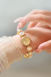 Gros plan sur la montre dorée pour femme avec bracelet en cristal et cadran champagne