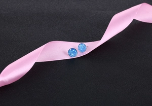 Macro shot of blue crystal cluster stud earrings on pink ribbon and black background