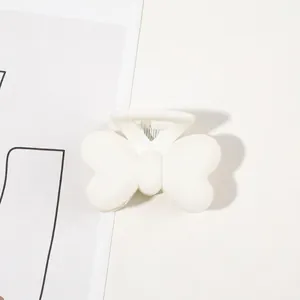 Detailed close-up of a matte white bow-shaped hair claw clip with a strong metal spring