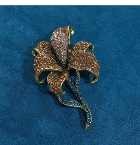Detail of amber lily flower brooch with rhinestones on dark blue textured fabric