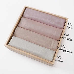 Solid cotton scarves in pink, soft pink, orange pink, and cream on a wooden tray