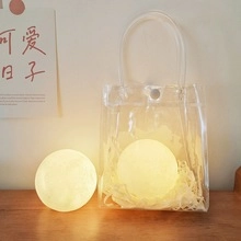 Detailed gift packaging of moon lamps in transparent PVC bags with warm yellow glow