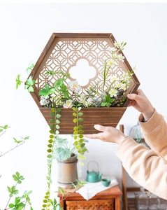 Detalle de jardinera de pared hexagonal de madera con plantas y elegante celosía