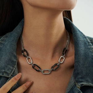 Dettaglio di collana a catena argento con maglie ovali nere e trasparenti su una modella