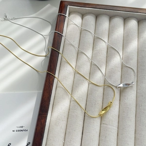 Macro view of gold and silver S925 snake bone necklaces with twisted pendant in a wooden box