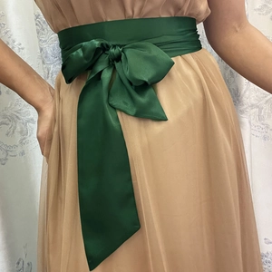Ceinture large en satin vert foncé nouée en ruban sur une robe en mousseline