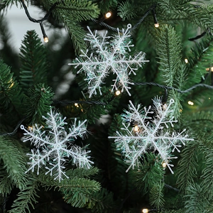 White iridescent tinsel snowflake ornaments hanging on a festive Christmas tree